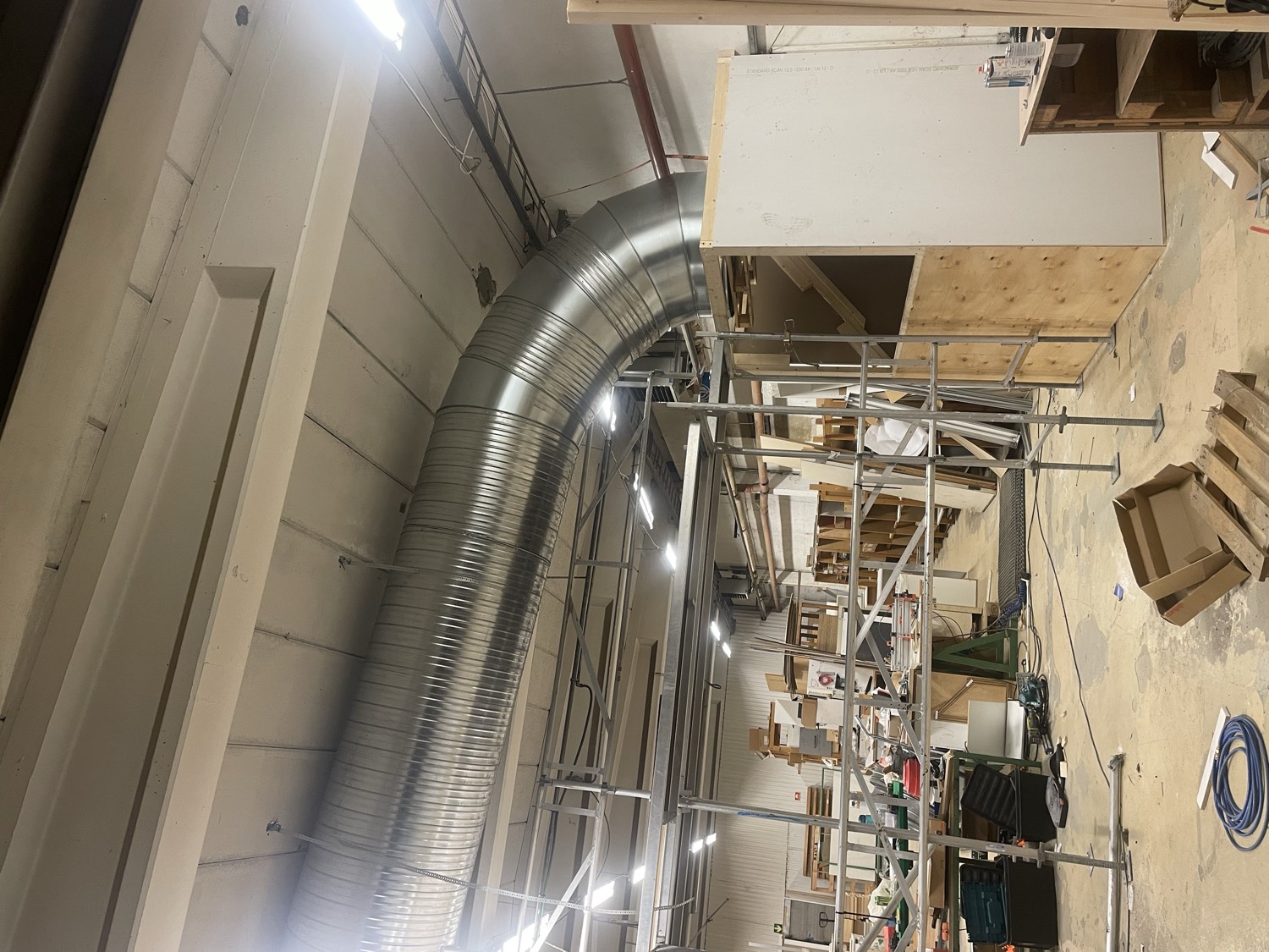 Large galvanised ducting carrying warm air from the miners through a heat-reuse workshop in Norway